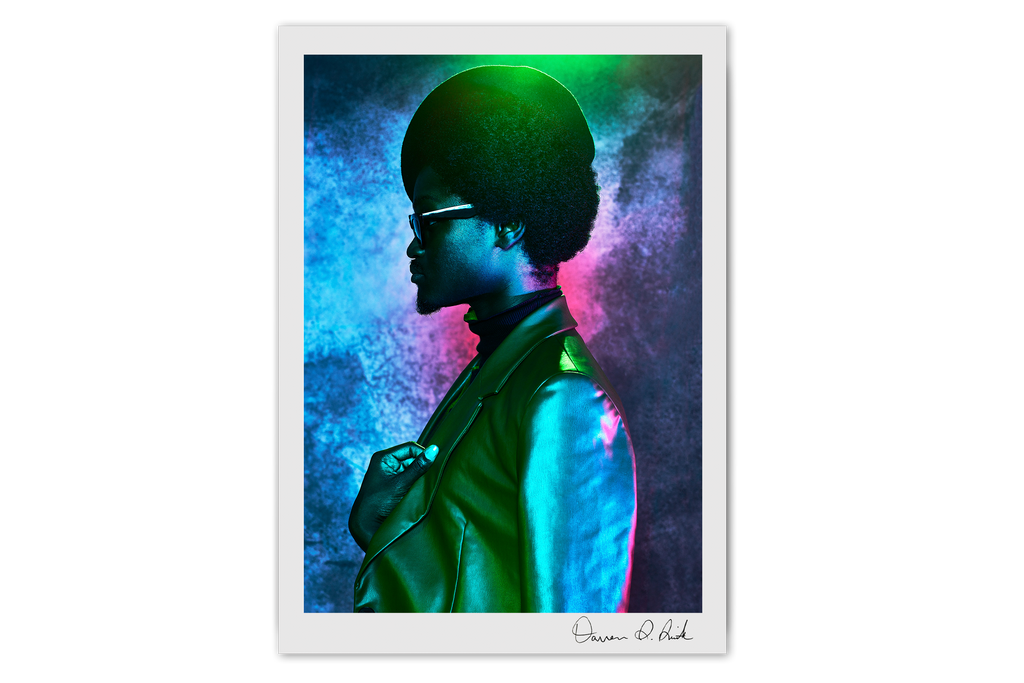 Print Special Edition: Utopia Ball Pt IV, dark-skinned male voguer with a stylish jacket and hat looking off camera with vibrant blue, red, and green lighting reflecting on his clothing and on the studio background
