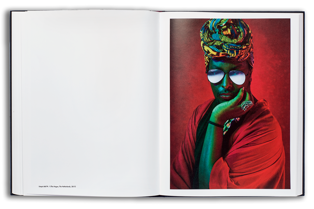 Mayflies book flat spread: male voguer with sunglasses with vibrant green lighting on his skin, looking directly at camera on a deep red background