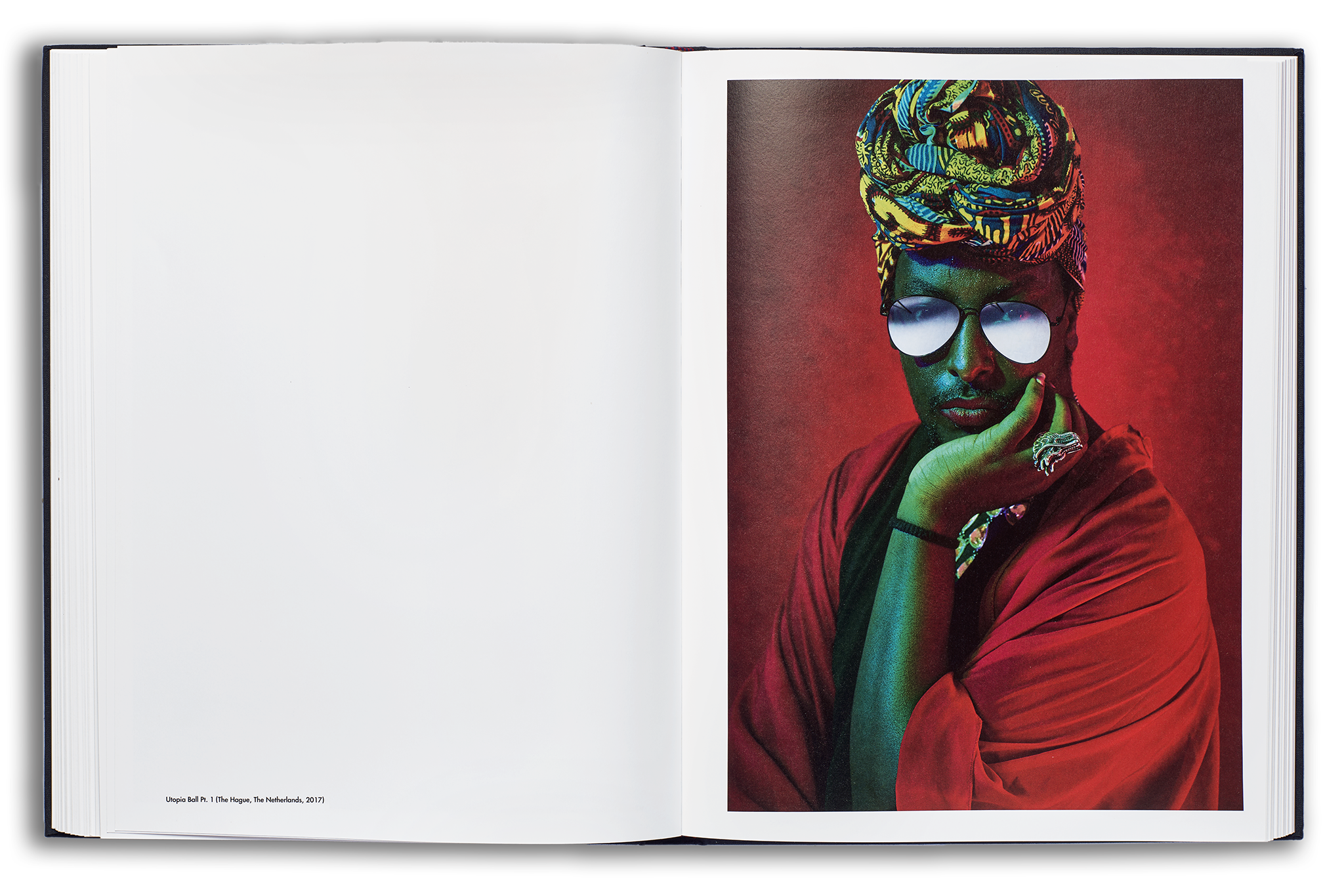 Mayflies book flat spread: male voguer with sunglasses with vibrant green lighting on his skin, looking directly at camera on a deep red background